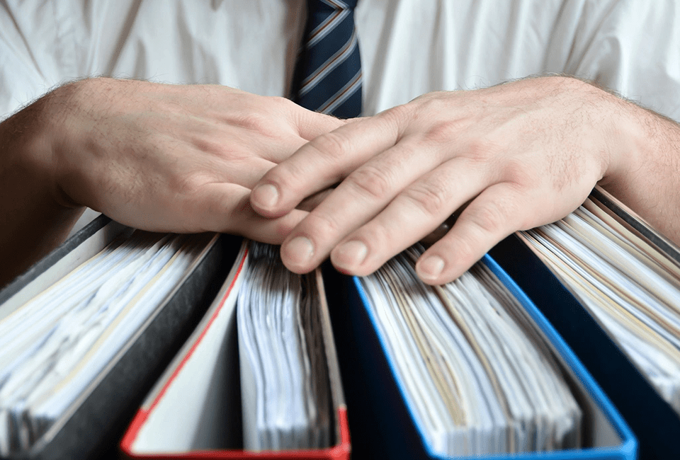 A man's hands holding a stack of files.